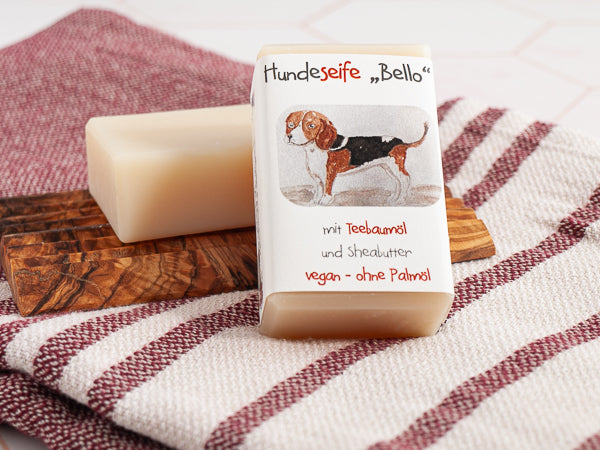 Zwei Bello Hunde-Seifen auf Tuch, mit und ohne Banderole, enthält Teebaumöl gegen Parasiten, lindert Juckreiz und Entzündungen